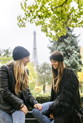 Frankreich, Paris, zwei beste Freunde sitzen in einem Park mit dem Eiffelturm im Hintergrund - MGOF03092