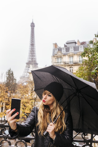 Frankreich, Paris, junge Frau macht ein Selfie mit dem Eiffelturm im Hintergrund, lizenzfreies Stockfoto