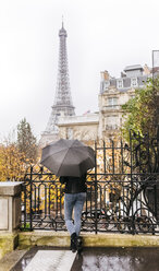 Frankreich, Paris, Frau unter Regenschirm mit dem Eiffelturm im Hintergrund - MGOF03100