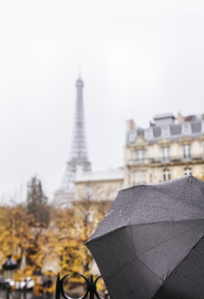 Frankreich, Paris, schwarzer Regenschirm mit dem Eiffelturm im Hintergrund - MGOF03101