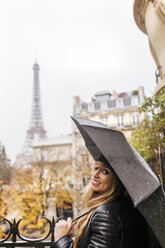 Frankreich, Paris, junge Frau unter Regenschirm mit dem Eiffelturm im Hintergrund - MGOF03102