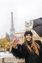 Frankreich, Paris, junge Frau macht ein Selfie mit dem Eiffelturm im Hintergrund - MGOF03104