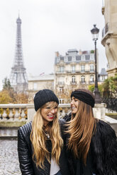 Frankreich, Paris, zwei beste Freunde gehen die Straße hinunter mit dem Eiffelturm im Hintergrund - MGOF03106