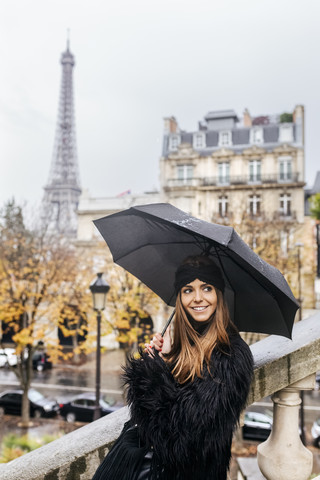 Frankreich, Paris, junge Frau unter Regenschirm mit dem Eiffelturm im Hintergrund, lizenzfreies Stockfoto