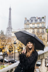 Frankreich, Paris, junge Frau unter Regenschirm mit dem Eiffelturm im Hintergrund - MGOF03107