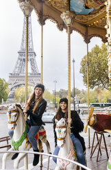 France, Paris, two best friends riding a carousel with the Eiffel Tower in the background - MGOF03113