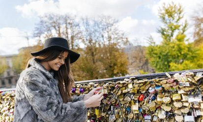 Frankreich, Paris, junge Frau, die ein Liebesschloss an einer Brücke über die Seine anbringt - MGOF03115