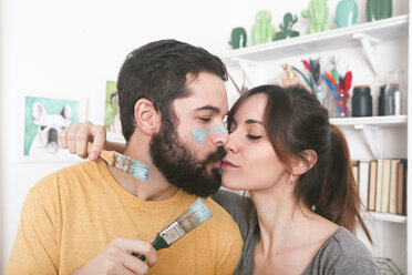 Young couple kissing holding paintbrushes - RTBF00782