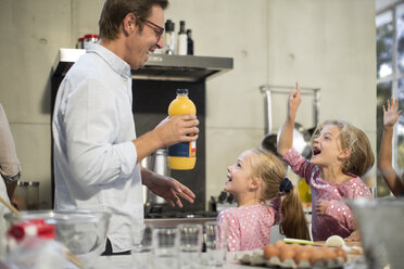Vater gibt Orangensaft an aufgeregte Mädchen in der Küche - ZEF13209