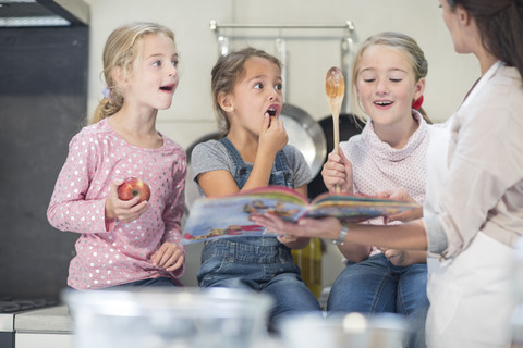 Mutter und drei Mädchen in der Küche, lizenzfreies Stockfoto