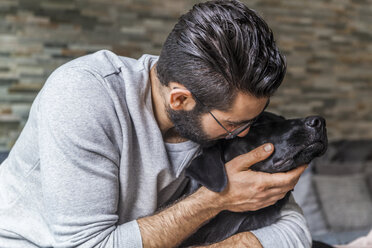 Man cuddling with his dog at home - TCF05319