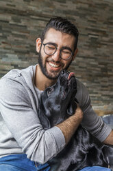 Porträt eines Mannes mit seinem Hund zu Hause - TCF05328