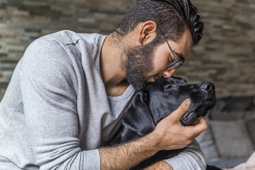 Mann kuschelt mit seinem Hund zu Hause - TCF05329