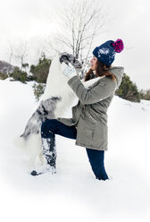 Junge Frau spielt mit ihrem Border Collie im Schnee - MGOF03137