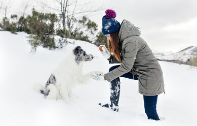 Young woman playing with her border collie in the snow - MGOF03138