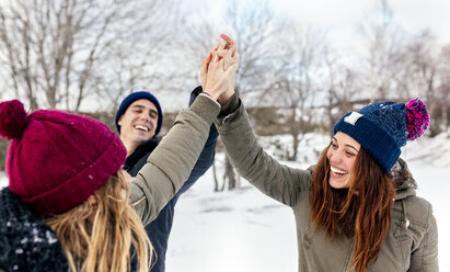 Drei Freunde reichen sich im Schnee die Hände - MGOF03150
