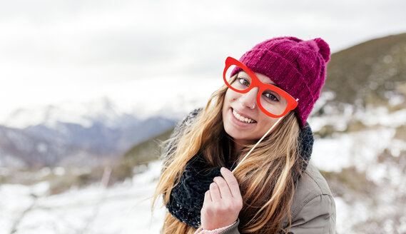 Junge Frau mit falscher Brille hat Spaß in den verschneiten Bergen - MGOF03153