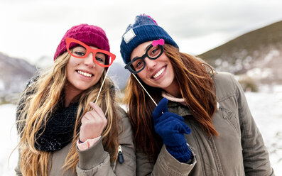 Zwei junge Frauen mit gefälschten Brillen haben Spaß in den verschneiten Bergen - MGOF03155