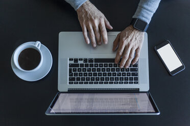 Top view of businessman at desk with laptop, smartphone and cup of coffee - TCF05357