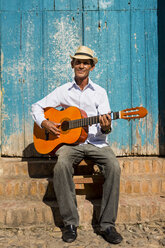 Cuba, portrait of man playing guitar on the street - MAUF01033
