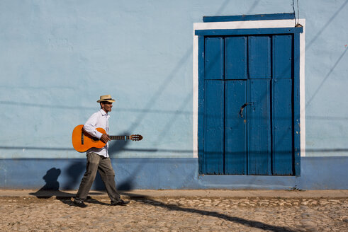 Cuba, man with guitar walking on the street - MAUF01035