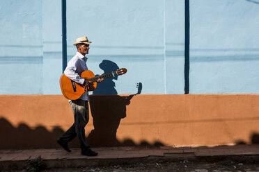 Cuba, man with guitar walking on the street - MAUF01036