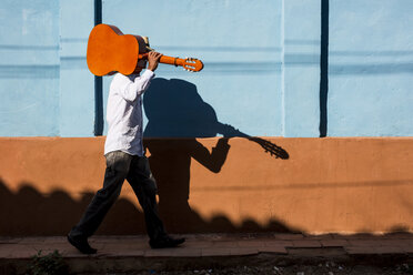 Cuba, man with guitar walking on the street - MAUF01038