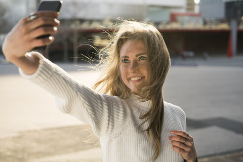 Porträt einer jungen Frau, die ein Selfie mit ihrem Smartphone macht - KKAF00548