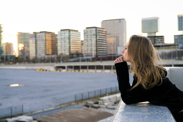 Spanien, Barcelona, nachdenkliche junge Frau lehnt an der Wand und schaut in die Ferne - KKAF00564