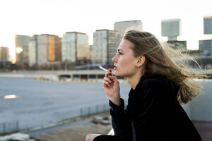 Spain, Barcelona, pensive young woman smoking cigarette - KKAF00566