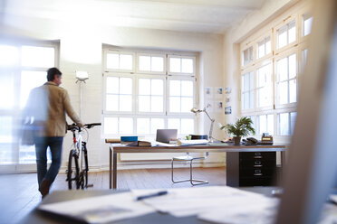 Mann mit Fahrrad in einem modernen informellen Büro - FKF02203