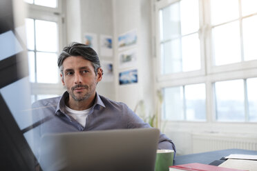 Man at desk in office thinking - FKF02217