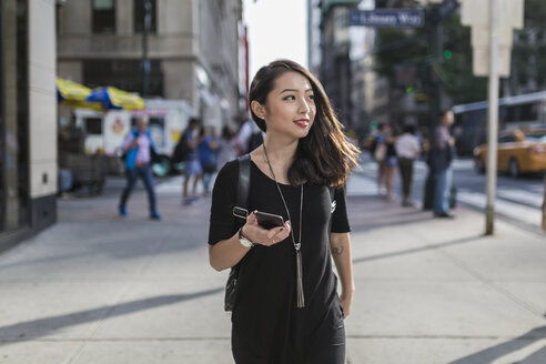 USA, New York City, Manhattan, Porträt einer jungen, schwarz gekleideten Frau mit Mobiltelefon - GIOF02483