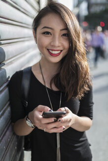 Porträt einer lächelnden jungen Frau mit Mobiltelefon - GIOF02487