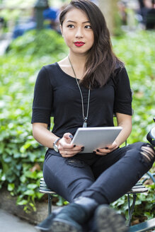 Porträt einer jungen Frau mit Tablet im Stadtpark - GIOF02498