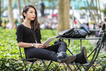 USA, New York, junge Frau mit Tablet im Stadtpark sitzend - GIOF02499