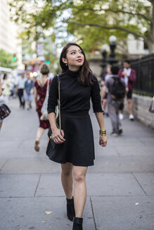USA, New York City, Manhattan, modische, schwarz gekleidete junge Frau geht auf dem Bürgersteig - GIOF02503