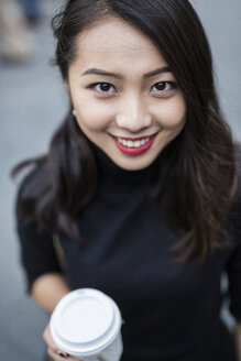 Porträt einer lächelnden jungen Frau mit Kaffee zum Mitnehmen - GIOF02512