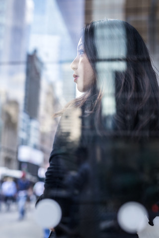 USA, New York City, Manhattan, träumende junge Frau hinter Glasscheibe, lizenzfreies Stockfoto