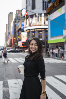 USA, New York City, Manhattan, glückliche junge Frau mit Kaffee zum Mitnehmen auf der Straße - GIOF02530