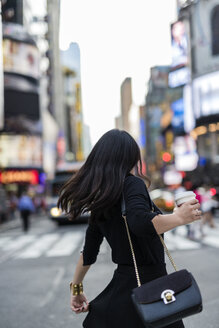 USA, New York City, Manhattan, Rückenansicht einer Frau mit Kaffee zum Mitnehmen auf der Straße - GIOF02532