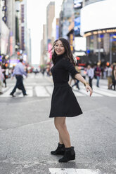 USA, New York City, Manhattan, glückliche, schwarz gekleidete junge Frau tanzt auf der Straße - GIOF02534