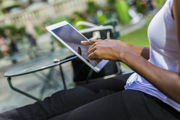 Woman sitting in a park using tablet, partial view - GIOF02537