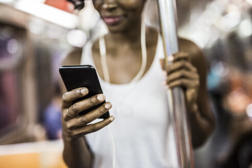 Frauenhand, die ein Handy in einem U-Bahn-Zug hält - GIOF02552