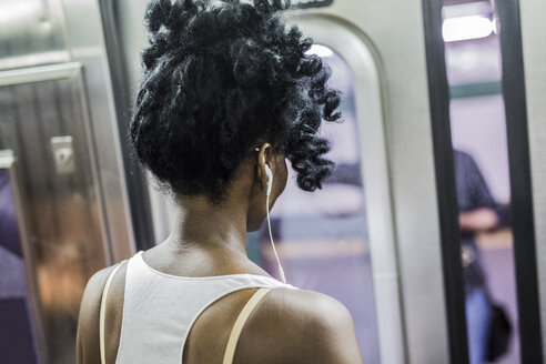 Rückenansicht einer Frau mit Kopfhörern in der U-Bahn - GIOF02555
