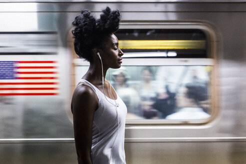 USA, New York City, Manhattan, Frau mit Kopfhörern auf dem Bahnsteig einer U-Bahn-Station - GIOF02556