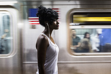 USA, New York City, Manhattan, woman with earphones on subway station platform - GIOF02557