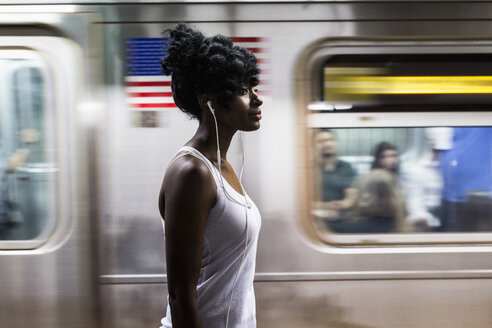 USA, New York City, Manhattan, Frau mit Kopfhörern auf dem Bahnsteig einer U-Bahn-Station - GIOF02557