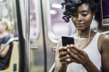 Portrait of woman looking at cell phone in underground train - GIOF02560