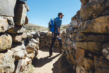 Bolivien, Titicacasee, Isla del sol, Mann mit Rucksack und Reiseführer bei einem Spaziergang zu den Chinkana-Ruinen - GEMF01548